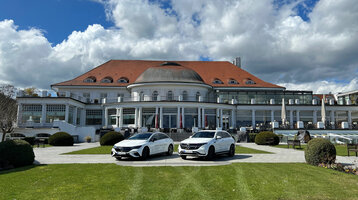 Historisches ATLANTIC Grand Hotel Travemünde mit rotem Dach, davor zwei weiße Autos auf gepflegtem Rasen.