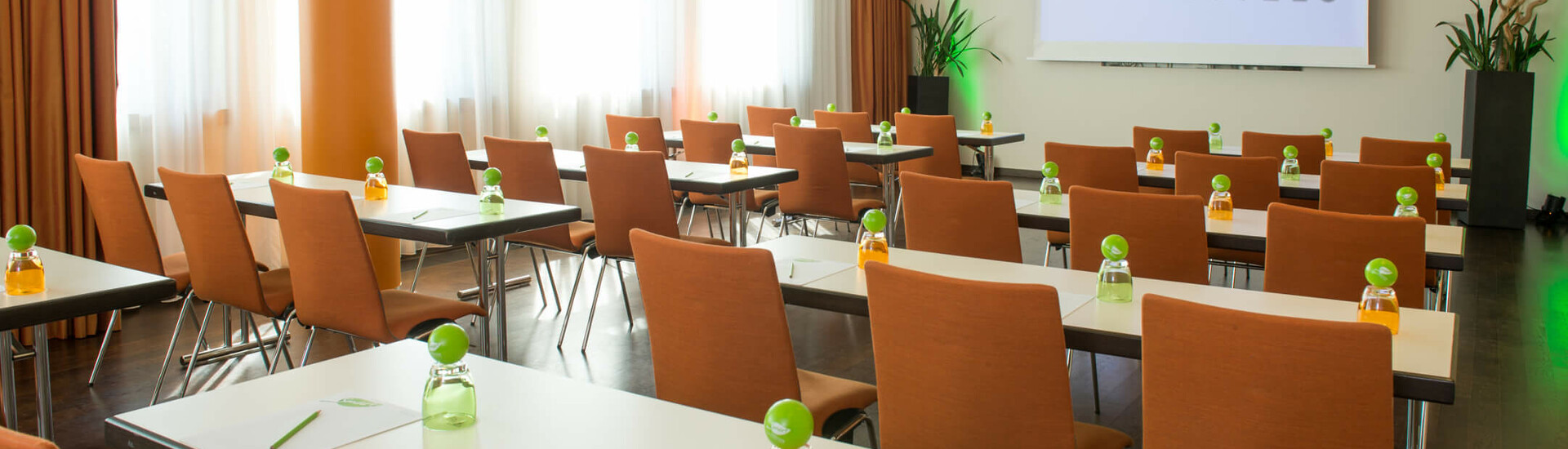 Moderner Konferenzraum im ATLANTIC Hotel Kiel mit Reihen aus Tischen, Stühlen und Getränken.