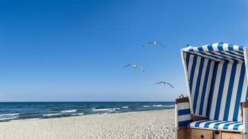 ATLANTIC Grand Hotel Travemünde – Beach chair © mbefoto – Fotolia Beach chair with blue stripes on the sandy beach, view of the sea and seagulls in the blue sky.