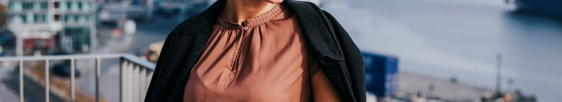 A woman is standing on her balcony, smiling as she looks out at the sun.