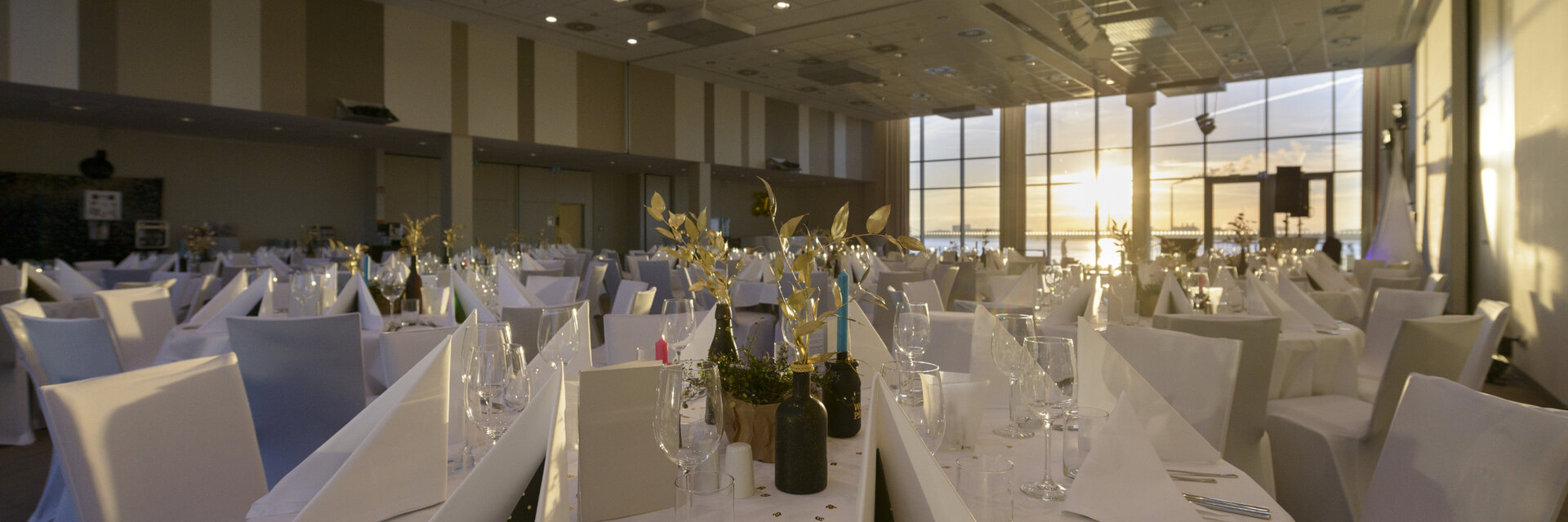 Elegant, festively decorated banquet hall in the ATLANTIC Hotel Sail City with a view of the sunset.