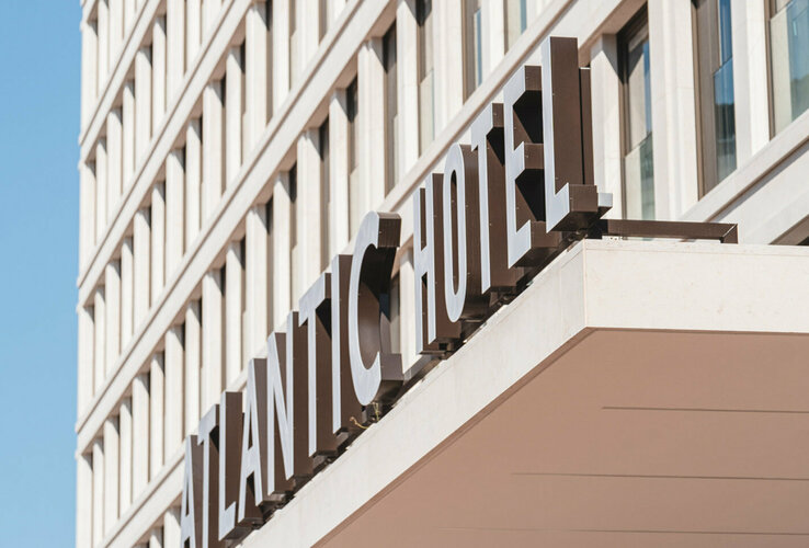 Fassade des ATLANTIC Hotel Heidelberg mit großem Schriftzug und modernen, rechteckigen Fenstern bei klarem Himmel.