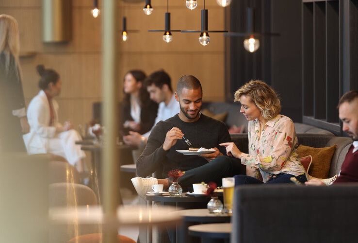 Menschen sitzen im Deli Café, essen Kuchen und trinken Kaffee.
