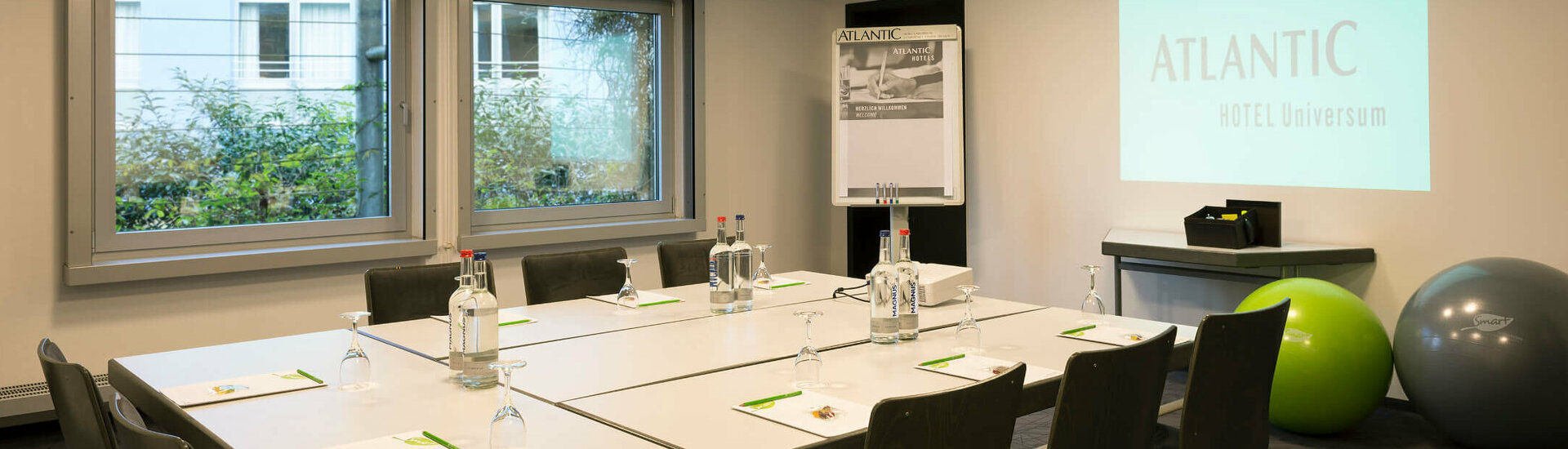 Meetings in conference room Saal 4 | ATLANTIC Hotel Universum Bremen Modern conference room in the ATLANTIC Hotel Universum, Bremen, with projector, flipchart and table for eight people.
