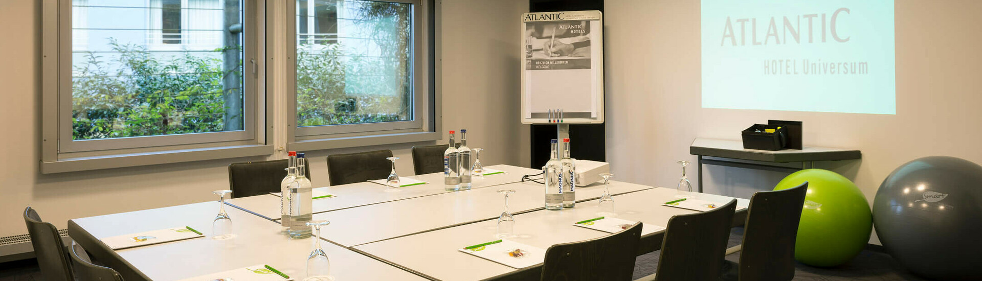 Tagungen und Meetings in Saal 4 | ATLANTIC Hotel Universum Bremen Moderner Konferenzraum im ATLANTIC Hotel Universum, Bremen, mit Projektor, Flipchart und Tisch für acht Personen.