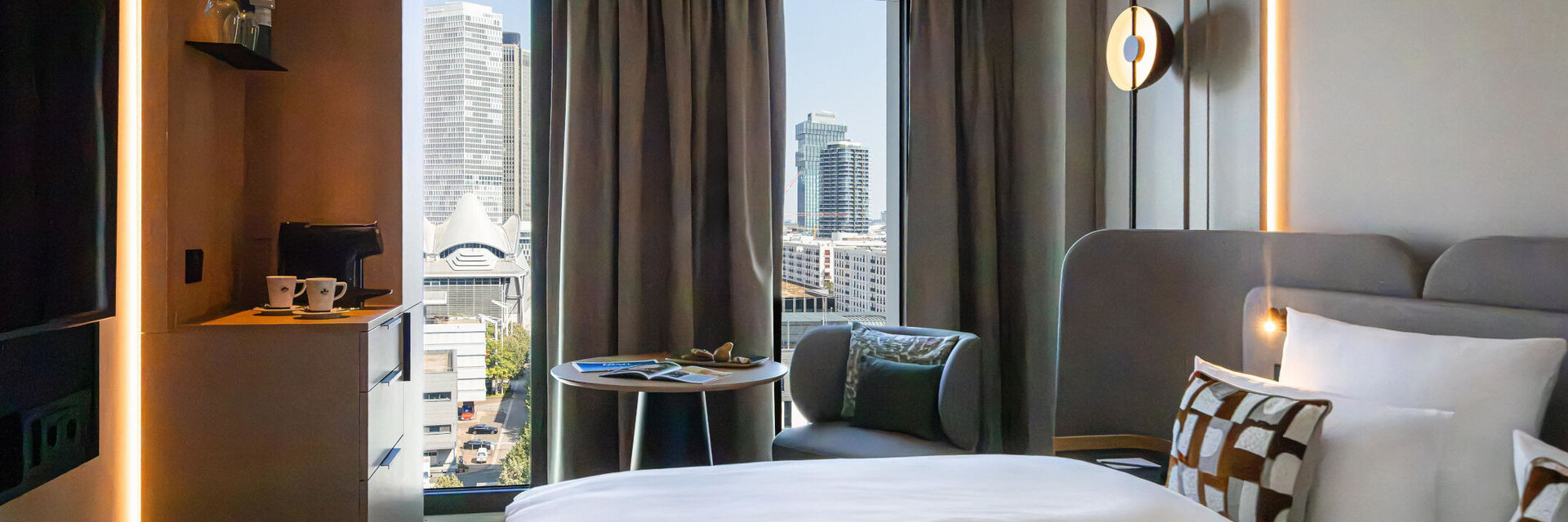 Ausblick auf die Frankfurter Skyline vom Bett im Skyline Zimmer.