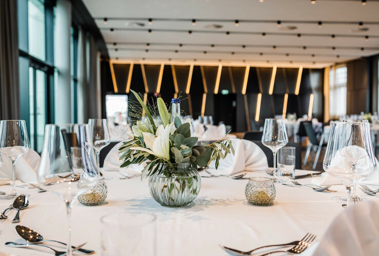 Eleganter Bankettsaal mit gedecktem Tisch, Blumenarrangement und stilvoller Beleuchtung im ATLANTIC Hotel Münster.
