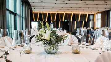 Engelsaal im ATLANTIC Hotel Münster Eleganter Bankettsaal mit gedecktem Tisch, Blumenarrangement und stilvoller Beleuchtung im ATLANTIC Hotel Münster.