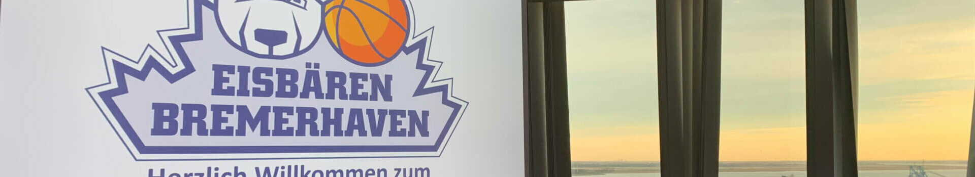 Konferenzraum im ATLANTIC Hotel Sail City mit Blick auf den Sonnenuntergang über dem Wasser, Logo der Eisbären Bremerhaven.