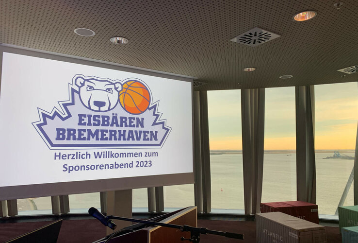 Konferenzraum im ATLANTIC Hotel Sail City mit Blick auf den Sonnenuntergang über dem Wasser, Logo der Eisbären Bremerhaven.
