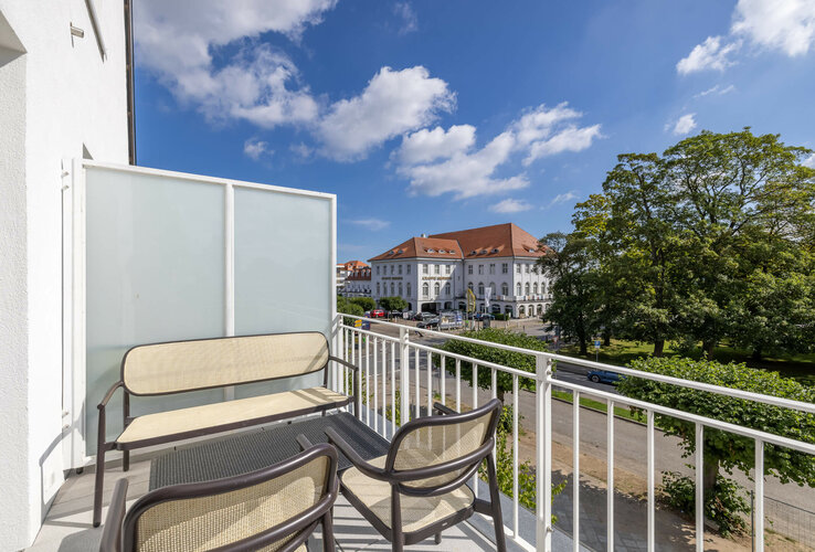 Balkonblick auf das ATLANTIC Grand Hotel Travemünde mit Garten und blauem Himmel.