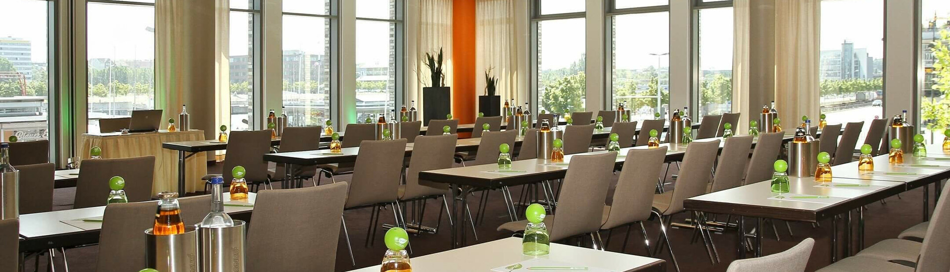 Heller Konferenzraum im ATLANTIC Hotel Kiel mit Tischen, Stühlen und Getränken, große Fenster mit Stadtblick.