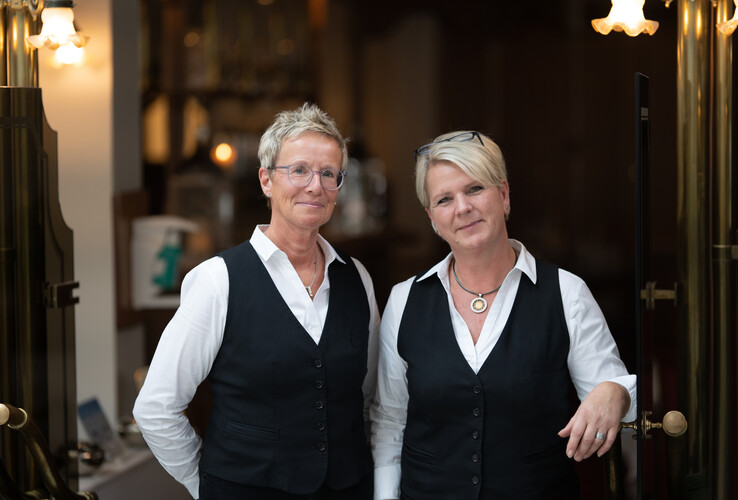 Zwei Mitarbeiterinnen in Uniform lächeln im Eingangsbereich des ATLANTIC Hotel Landgut Horn Bremen.