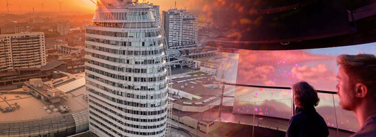 ATLANTIC Hotel Sail City bei Sonnenuntergang, moderne Architektur, zwei Personen genießen die Aussicht im Inneren.