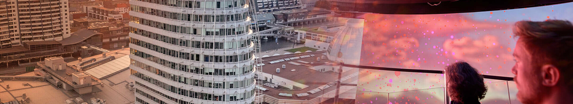 ATLANTIC Hotel Sail City Veranstaltungsprogramm im Klimahaus ATLANTIC Hotel Sail City bei Sonnenuntergang, moderne Architektur, zwei Personen genießen die Aussicht im Inneren.