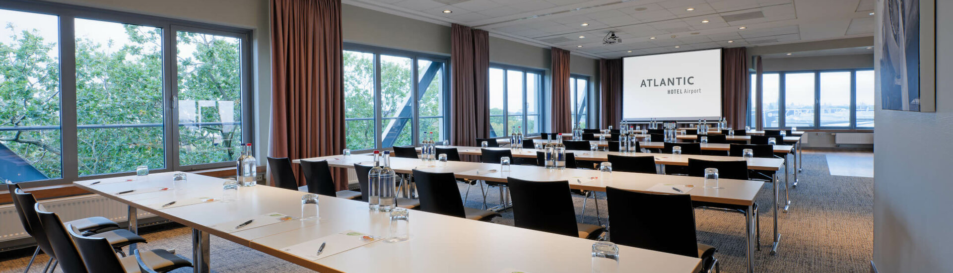 ATLANTIC Hotel Airport Conference Room Modern conference room at the ATLANTIC Hotel Airport Bremen with tables, chairs and a large screen.