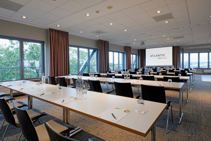 ATLANTIC Hotel Airport Conference Room Modern conference room at the ATLANTIC Hotel Airport Bremen with tables, chairs and a large screen.