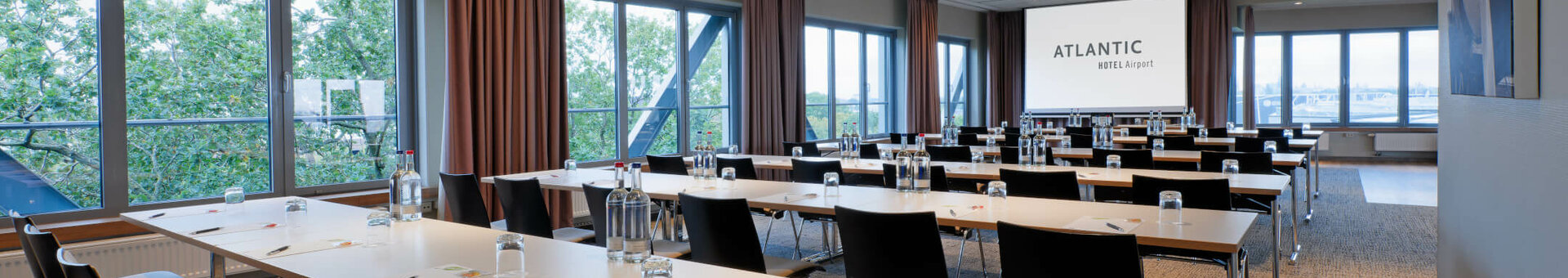 ATLANTIC Hotel Airport Conference Room Modern conference room at the ATLANTIC Hotel Airport Bremen with tables, chairs and a large screen.