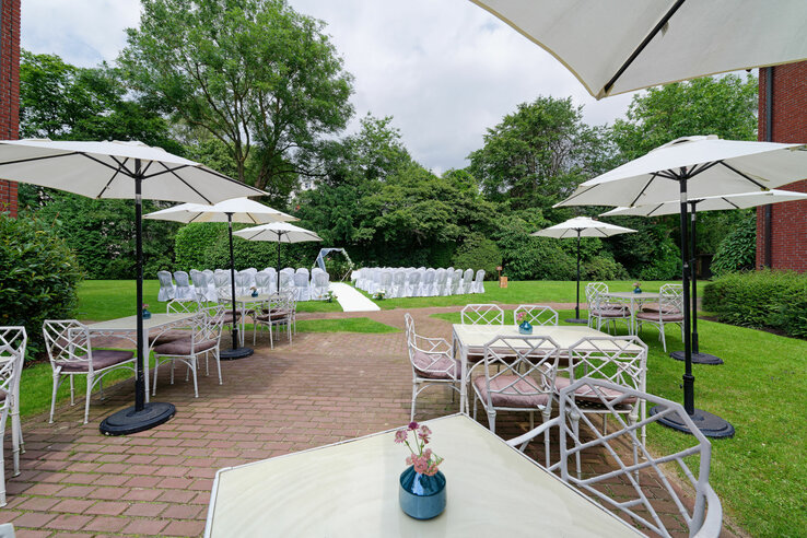 Garden area of the ATLANTIC Hotel with covered tables, parasols and chairs for an outdoor event.