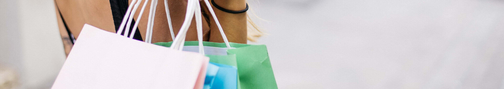 A woman is holding several colourful shopping bags in her hand.