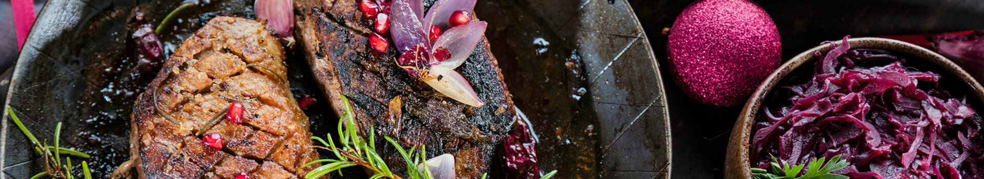 Heiligabend-Buffet im ATLANTIC Hotel Wilhelmshaven Zwei gebratene Entenbrüste mit Granatapfel und Rosmarin, serviert mit Rotkohl, festlich dekoriert.