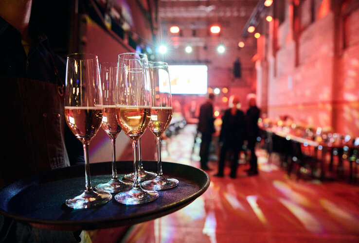 A tray with champagne glasses in an atmospherically lit event room.