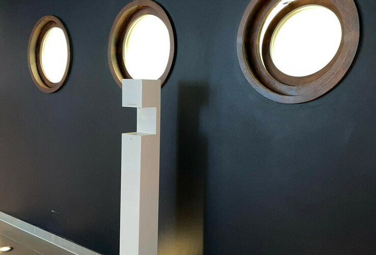 Three porthole windows in a dark wall, next to a white, modern sculpture in the ATLANTIC Hotel Sail City.