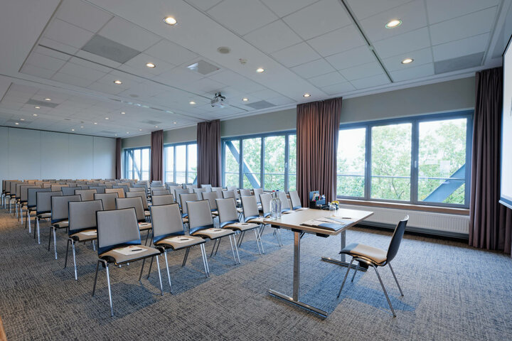 ATLANTIC Hotel Airport Conference Room Bright conference room in the ATLANTIC Hotel Airport Bremen with rows of chairs, table and large windows with a view of the greenery.