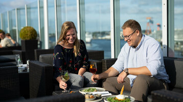 Ein Paar speist bei guten Wetter auf der Dachterrasse von der Bar Deck 8 Kiel