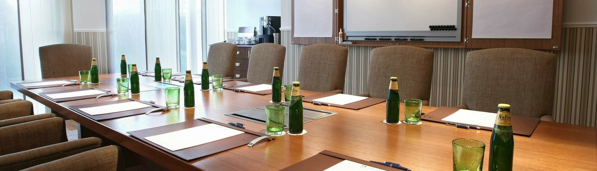 Modern conference room at the ATLANTIC Grand Hotel Travemünde with large table, chairs, flipchart and drinks.