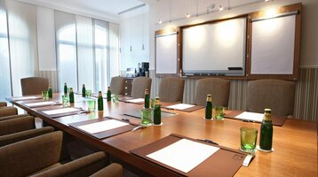 Conference room in the ATLANTIC Grand Hotel Travemünde Modern conference room at the ATLANTIC Grand Hotel Travemünde with large table, chairs, flipchart and drinks.