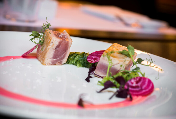 Gourmet-Teller mit Thunfisch, Rote Bete und grünen Kräutern kunstvoll angerichtet auf weißem Teller.