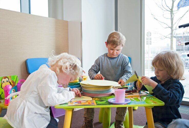 Kinder basteln an einem Tisch im Spielbereich des ATLANTIC Hotel Kiel.