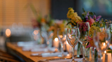 Elegant gedeckter Tisch im ATLANTIC Hotel Bremen mit Blumen, Kerzen und Weingläsern in stimmungsvoller Beleuchtung.