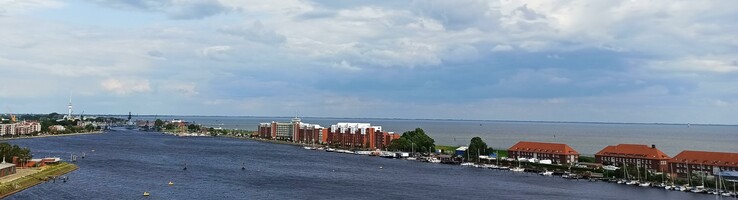 View of the port of Wilhelmshaven with red brick buildings, water and cloudy sky.