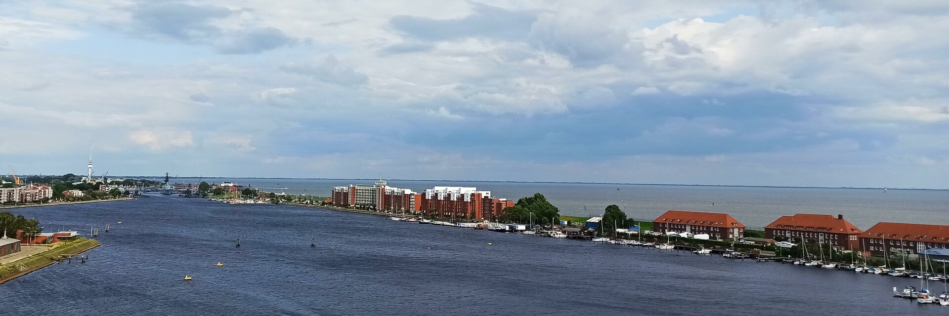 View of the port of Wilhelmshaven with red brick buildings, water and cloudy sky.