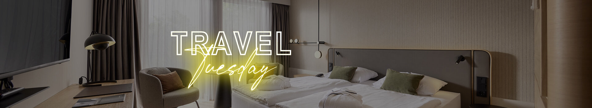 Modernes Hotelzimmer mit zwei Einzelbetten, Schreibtisch, Sessel und großen Fenstern mit Vorhängen.