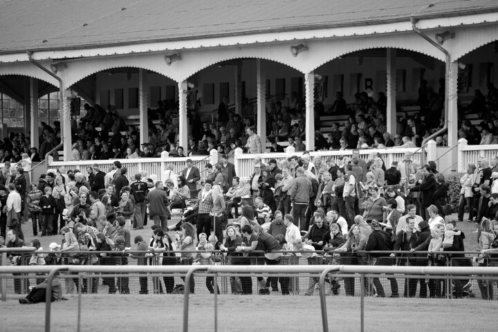 Besucher auf der Tribüne und im Freien bei einer Pferderennbahn-Veranstaltung in Bremen.