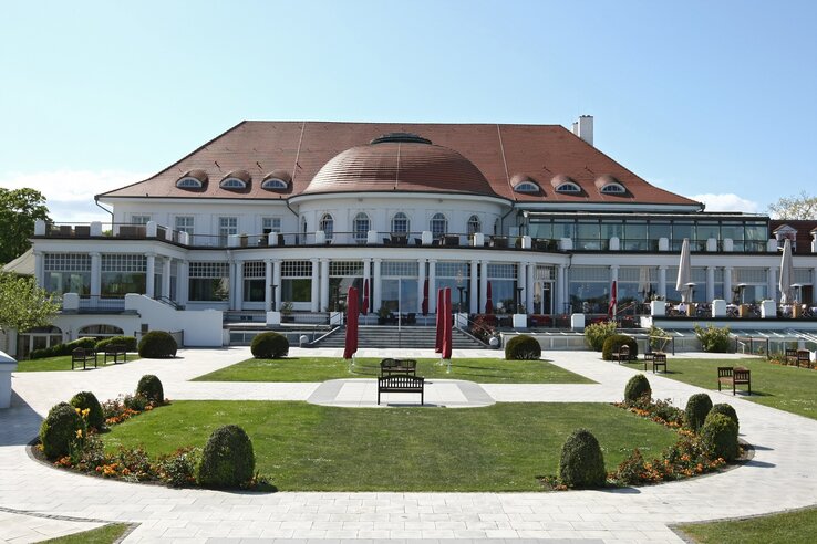 The ATLANTIC Grand Hotel Travemünde with its well-tended garden and red parasols in front of the elegant façade.