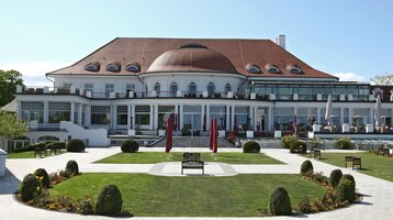 ATLANTIC Grand Hotel Travemünde exterior view with park The ATLANTIC Grand Hotel Travemünde with its well-tended garden and red parasols in front of the elegant façade.