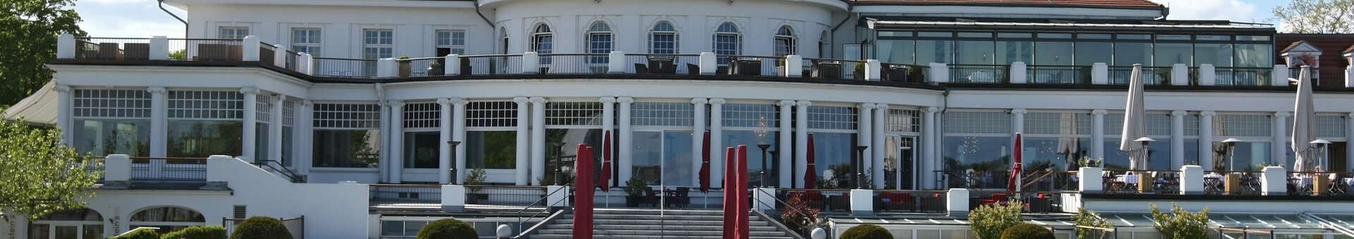 ATLANTIC Grand Hotel Travemünde exterior view with park The ATLANTIC Grand Hotel Travemünde with its well-tended garden and red parasols in front of the elegant façade.
