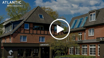 ATLANTIC Hotel Landgut Horn Bremen  Backsteinfassade des ATLANTIC Hotel Landgut Horn Bremen mit Fachwerkdetails, umgeben von Bäumen unter blauem Himmel.