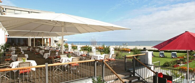 ATLANTIC Grand Hotel Travemünde terrace with a view over the Baltic Sea Hotel terrace with tables and chairs, view of the Baltic Sea, sunshades, well-tended garden with beach chairs.