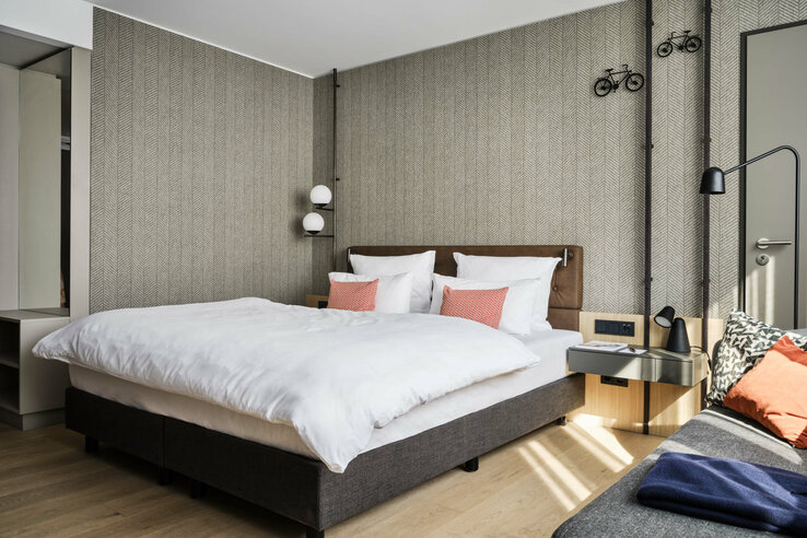 Modern hotel room with double bed, stylish lighting, elegant wallpaper and decorative bicycle motifs on the wall.