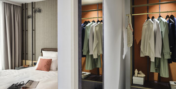 Modernes Hotelzimmer mit gemütlichem Bett, offener Garderobe und stilvollen Details im ATLANTIC Hotel Münster.