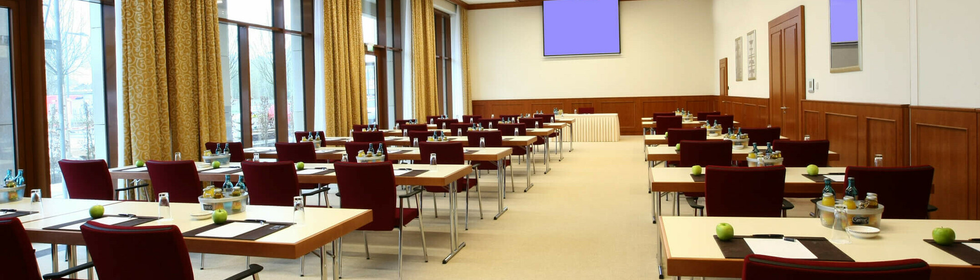 Veranstaltungsraum für Tagungen und Events Moderner Konferenzraum im ATLANTIC Hotel Wilhelmshaven, mit Tischen, Stühlen, Notizblöcken und Getränken.