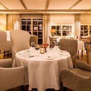 Elegant restaurant with a table setting, cozy armchairs and soft lighting at Severin*s Resort & Spa on Sylt.