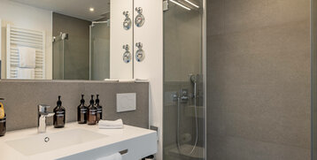Modern bathroom at the ATLANTIC Grand Hotel Travemünde with glass shower, washbasin and towel rail.