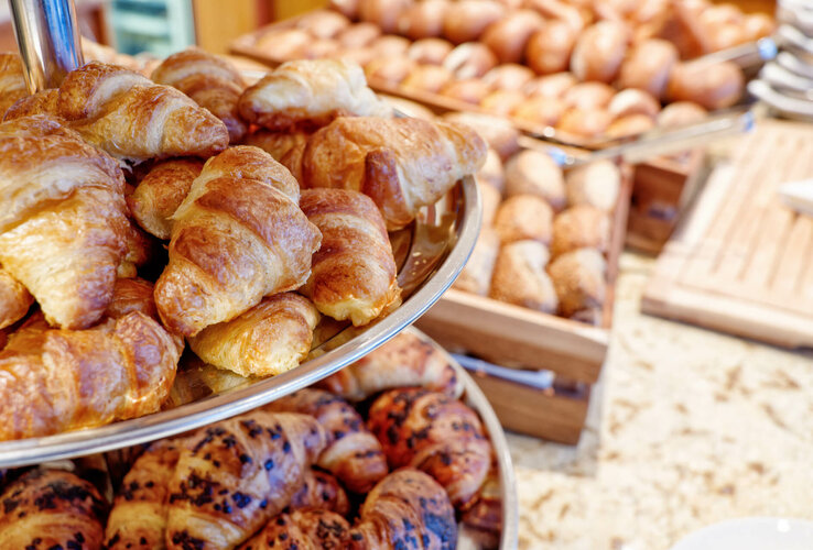 Frische Croissants und Brötchen auf einem Frühstücksbuffet im Hotel.