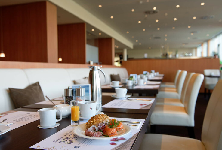 Breakfast table at the ATLANTIC Hotel with salmon, rolls, coffee and juice in a modern, bright restaurant.
